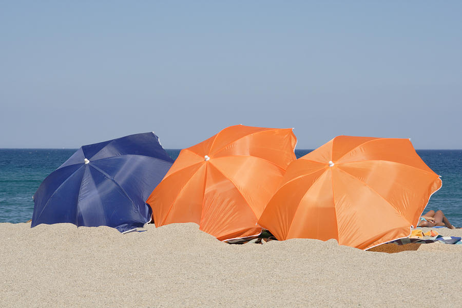 Beach with orange and blue parasols Photograph by Pejft