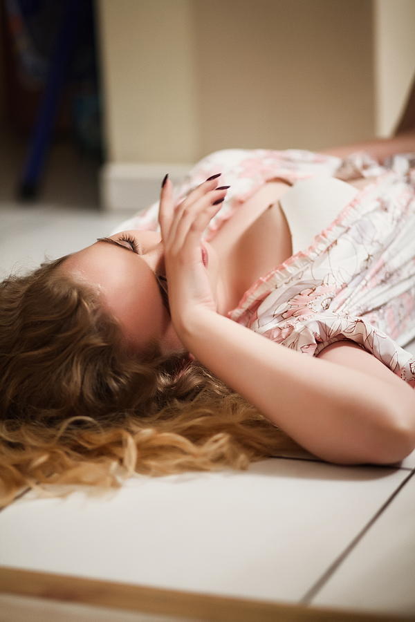Beautiful blond girl lies on the floor in the room. Photograph by Anton Petukhov