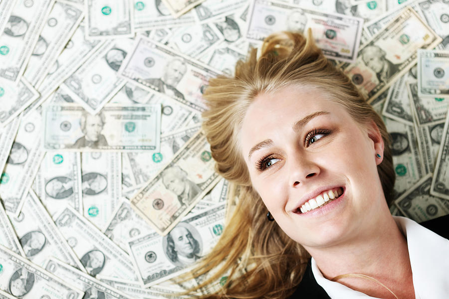 Beautiful blonde on US dollar background smiles happily Photograph by RapidEye