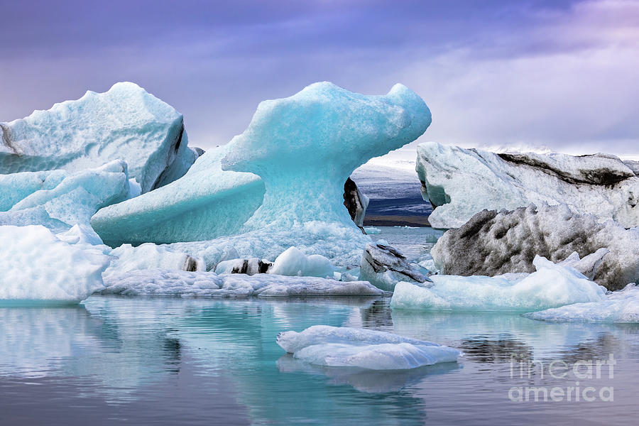 Beautiful blue icebergs reflected in the Jokulsarlon glacial lag Photograph by Jane Rix