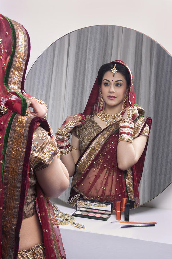Beautiful bride looking at herself in mirror Photograph by IndiaPix/IndiaPicture