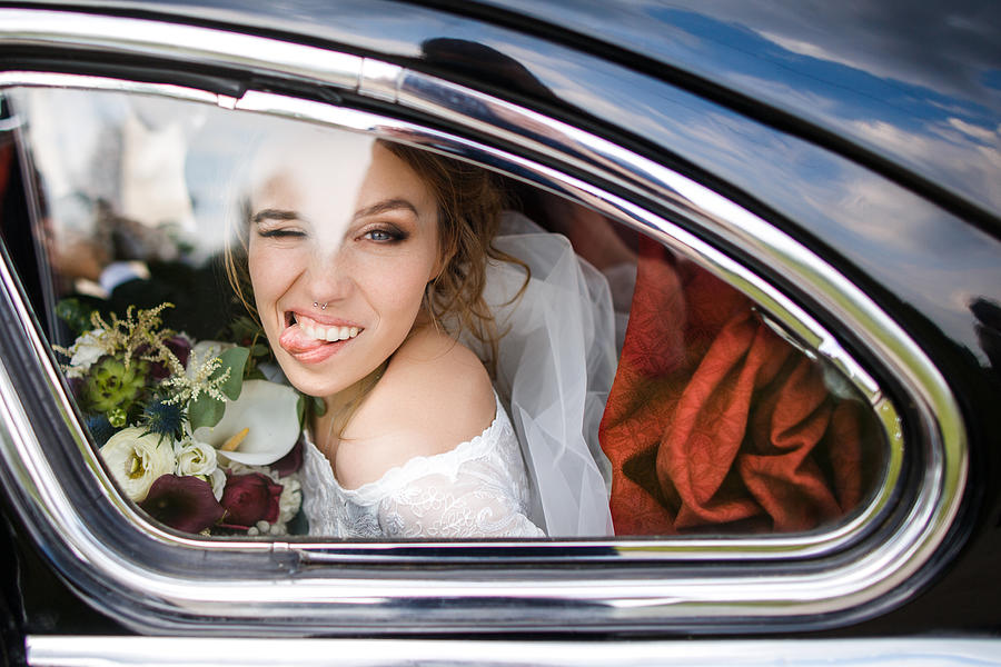 Beautiful bride shows tongue sitting in the car Photograph by Victor Dyomin