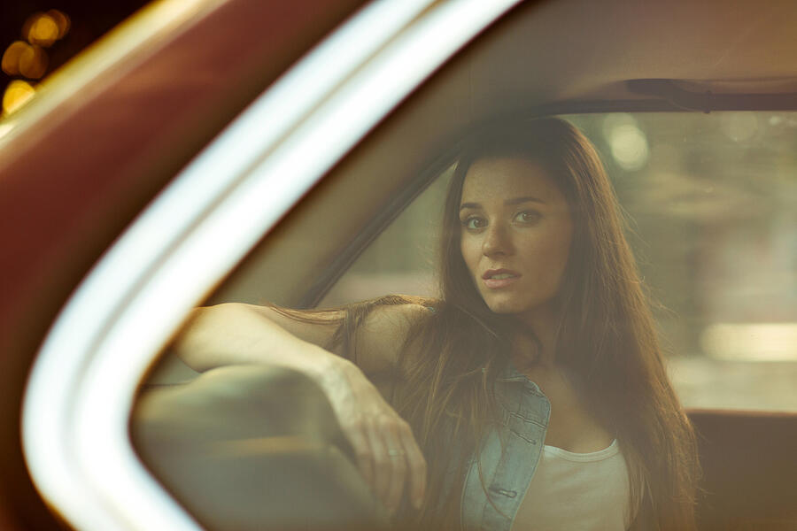 Beautiful brunette behind closed car window, tinted photo Photograph by Snedorez