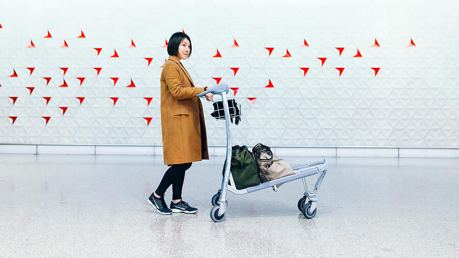Beautiful businesswoman with trolley in airport Photograph by Oscar Wong