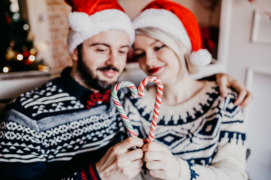 Beautiful couple making heart shape from Christmas candy cane Photograph by Anchiy