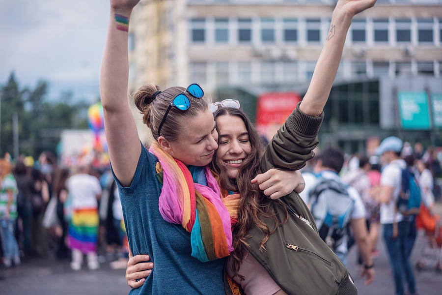 Beautiful female couple hugging while marching on the street Photograph by Mixmike