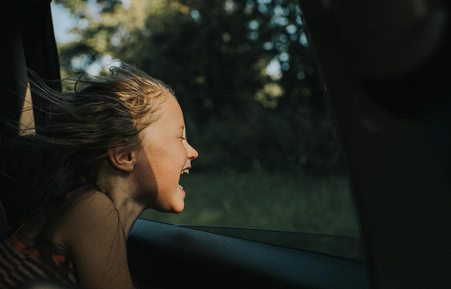 Beautiful happy little girl enjoying a car journey as the wind blows through her hair Photograph by Catherine Falls Commercial