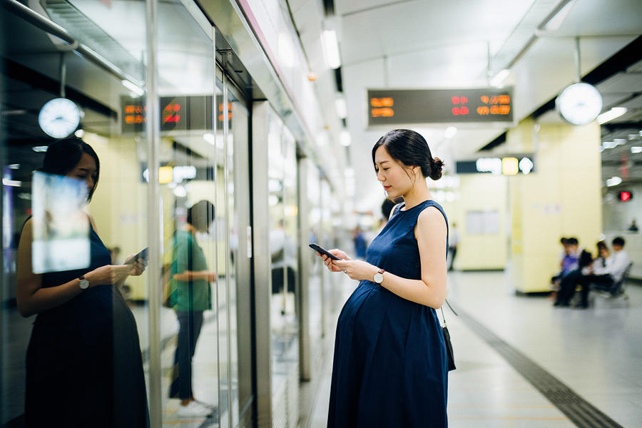 Beautiful pregnant woman using smartphone on platform while waiting for the train Photograph by D3sign