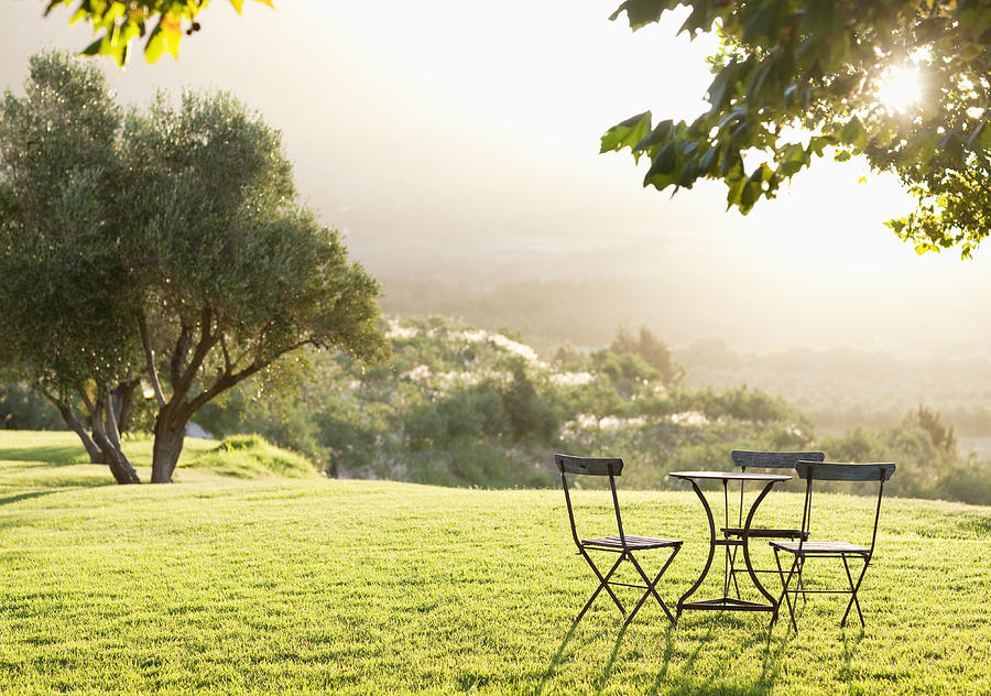 Beautiful view of lawn with empty table and chairs Photograph by OJO Images