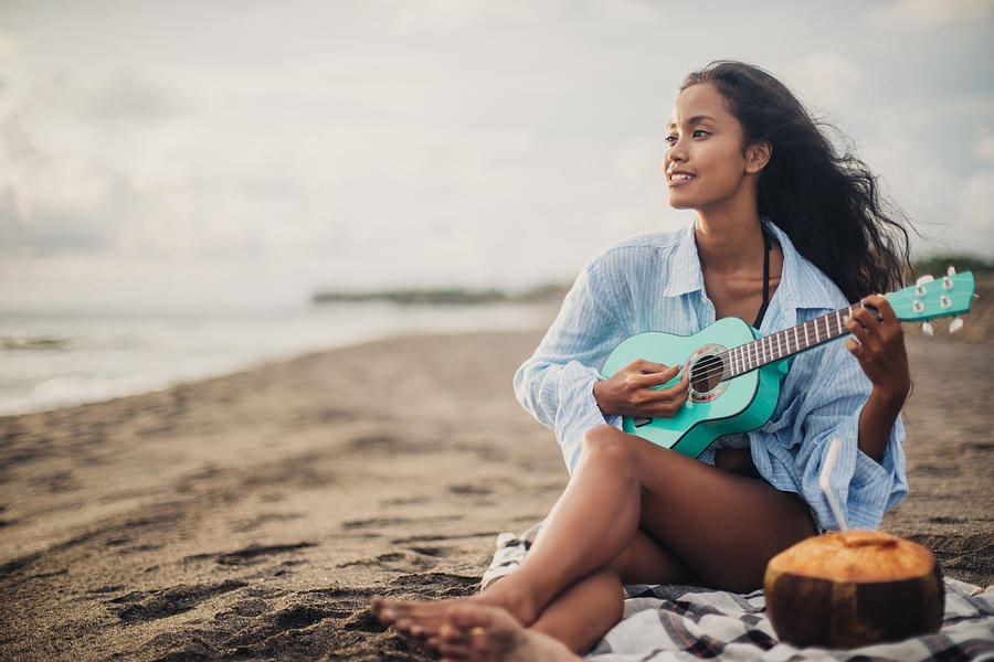 Beautiful woman playing ukulele at the beach Photograph by South_agency