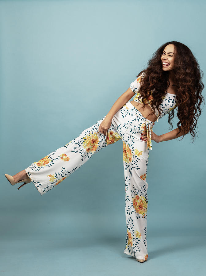 Beautiful woman with long curly hair in floral outfit front of blue background Photograph by Husam Cakaloglu