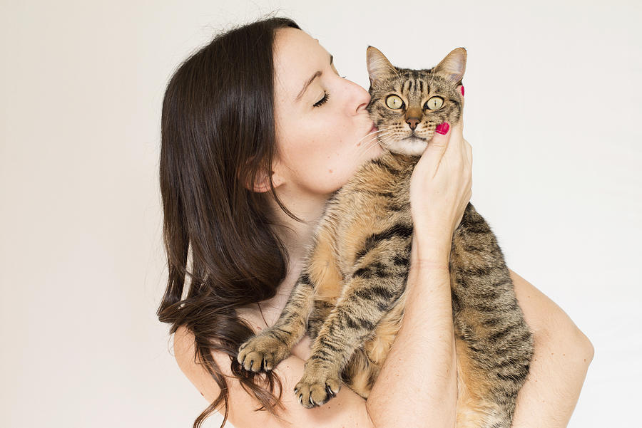 Beautiful young woman kissing a cute striped cat Photograph by Volanthevist