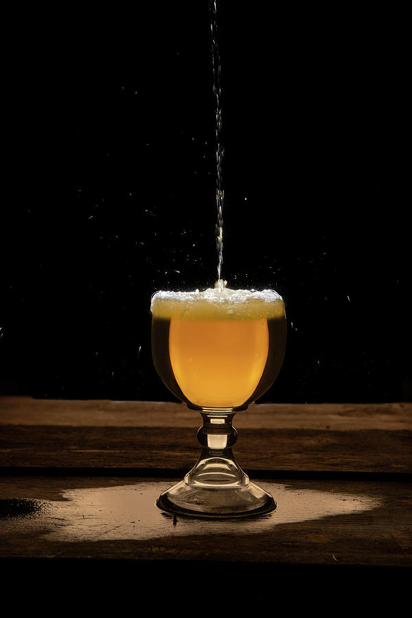 Beer being poured into glass from above Photograph by Dan Friend