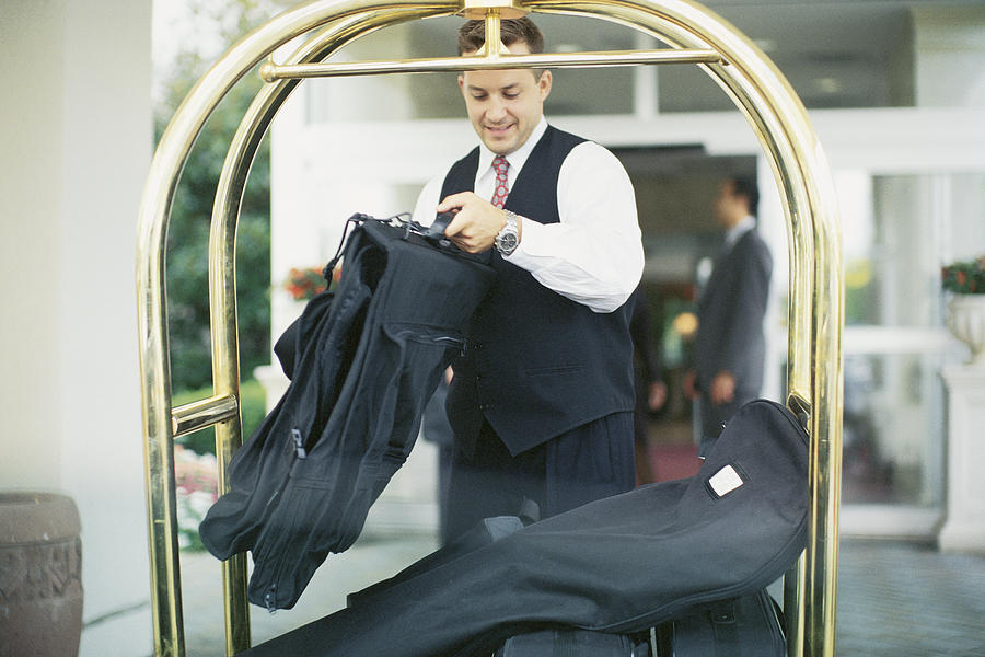 Bellboy with luggage cart Photograph by Comstock