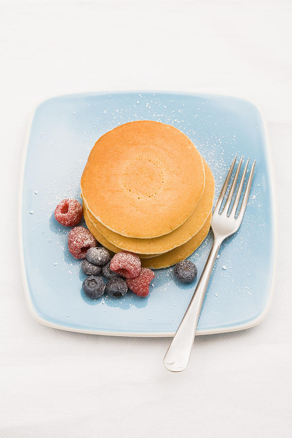 Berries and sugar on stack of pancakes Photograph by Tiina & Geir