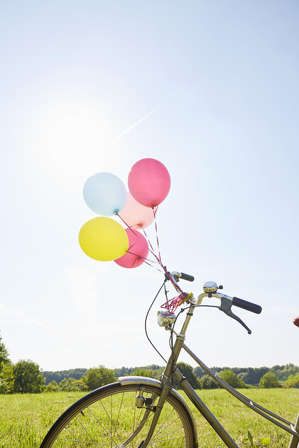 Bicycle with colorful balloons on a meadow against sky Photograph by The_burtons