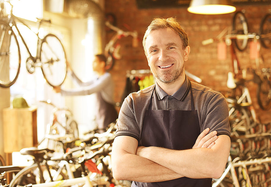 Bike Shop Owner Stands Proudly In Front Of His Stock Photograph by Sturti