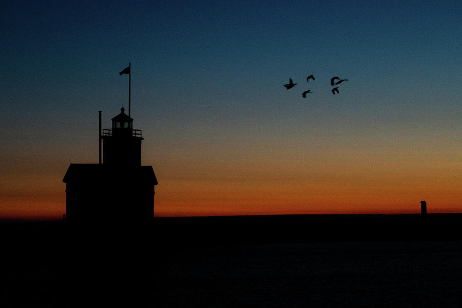 Birds flying at sunset next to the Holland Michigan Lighthouse Photograph by Eldon McGraw