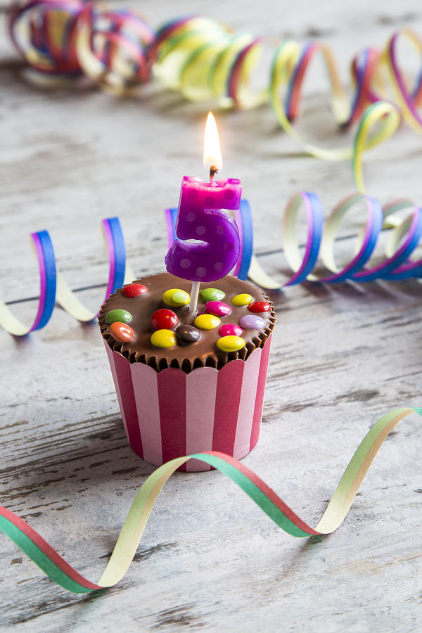 Birthday muffin with chocolate buttons and lighted candle Photograph by Westend61