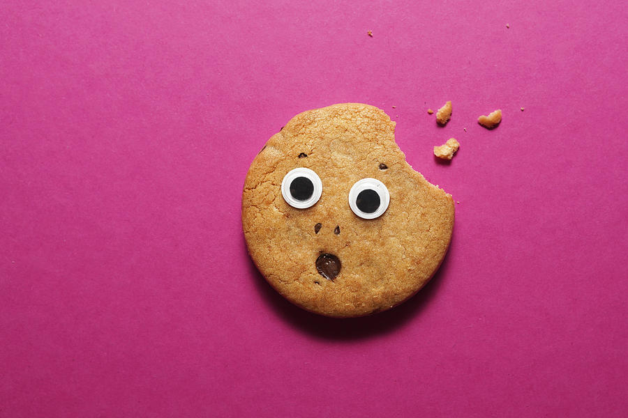 Biten cookie with eyes and frightened face on pink background Photograph by Volanthevist