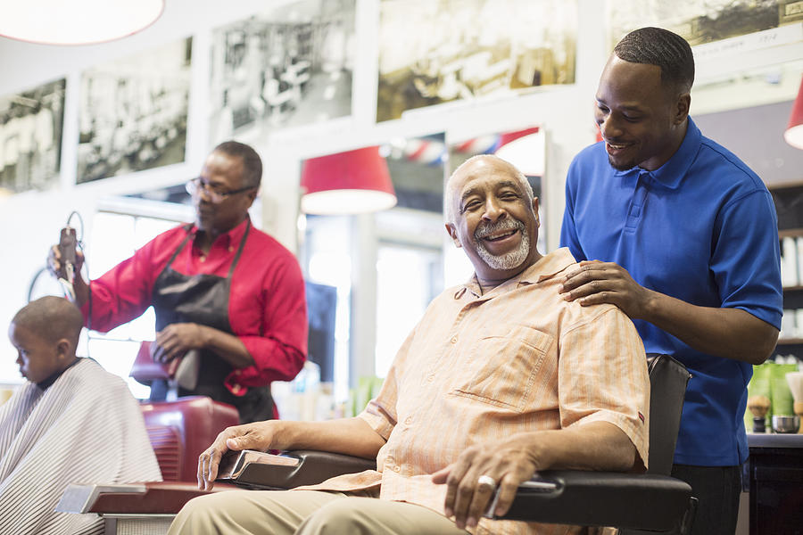 Black barber talking to customer in retro barbershop Photograph by Jetta Productions Inc