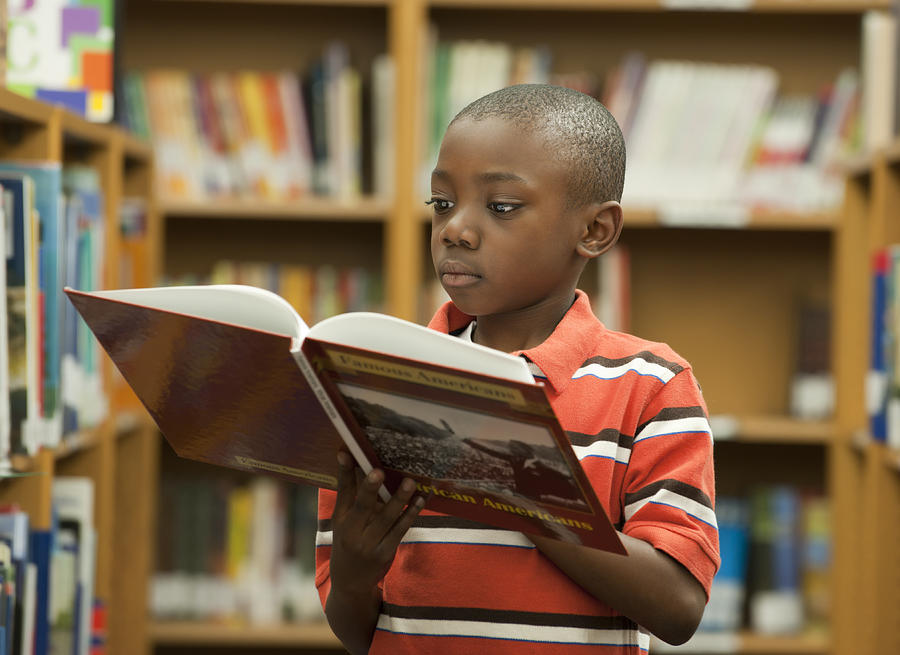 Black boy reading book in library Photograph by Ariel Skelley