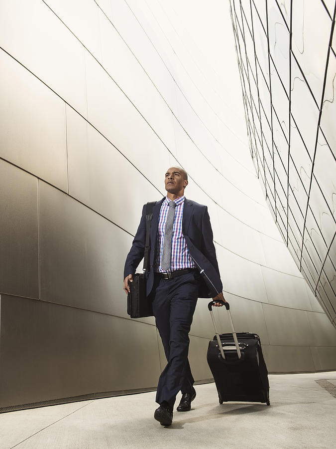 Black businessman rolling luggage Photograph by Erik Isakson