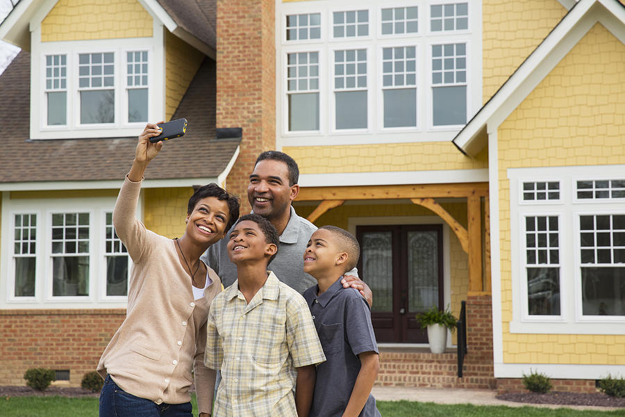 Black family taking pictures outside home Photograph by Ariel Skelley