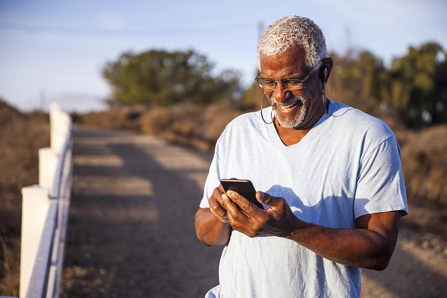 Black Man using smartphone on mountain trail Photograph by Adamkaz