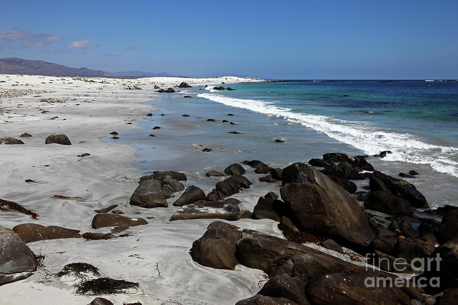 Black rocks on a white sand beach Chile Photograph by James Brunker