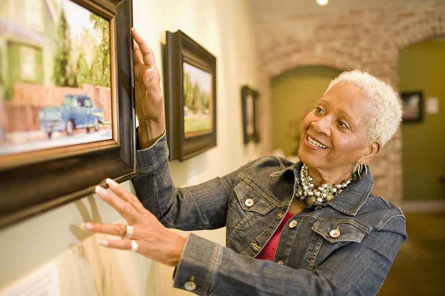 Black woman admiring painting in gallery Photograph by Chicasso