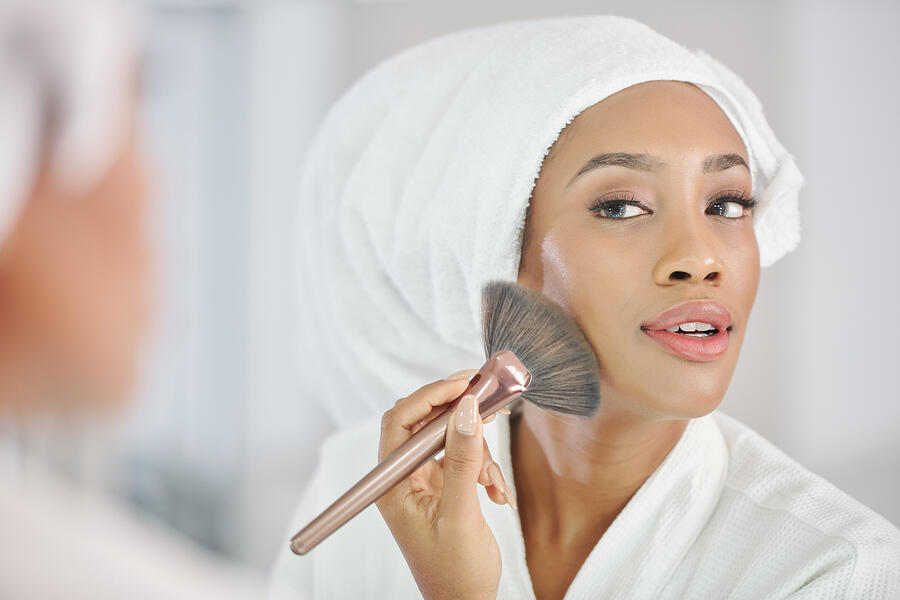 Black woman applying make-up Photograph by DragonImages