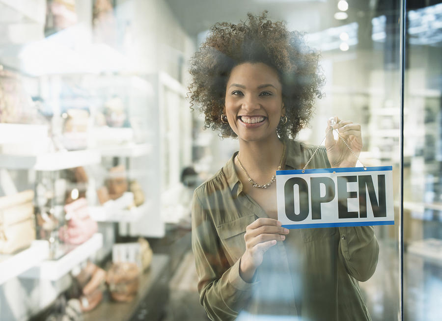 Black woman holding open sign in store window Photograph by Jose Luis Pelaez Inc