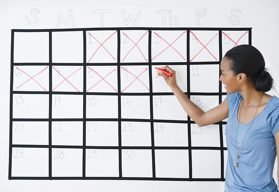Black woman marking the days off calendar Photograph by JGI/Jamie Grill