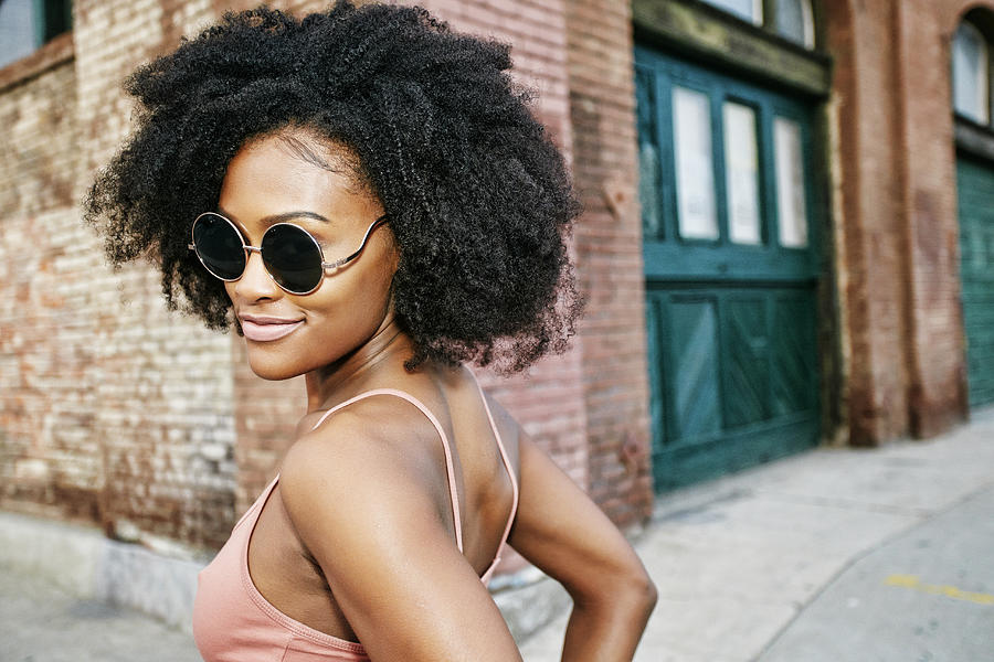 Black woman smiling near corner of brick building Photograph by Peathegee Inc