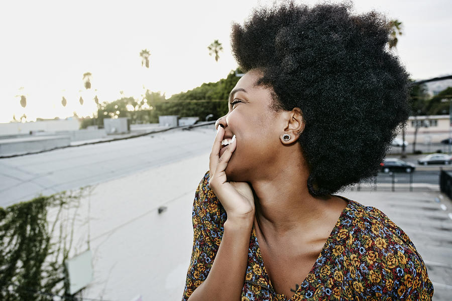 Black woman smiling on urban rooftop Photograph by Peter Griffith