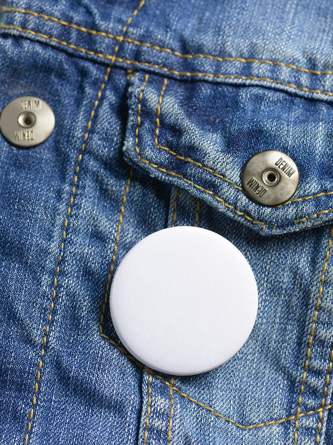 Blank button badge on denim jeans jacket. Photograph by Peter Dazeley