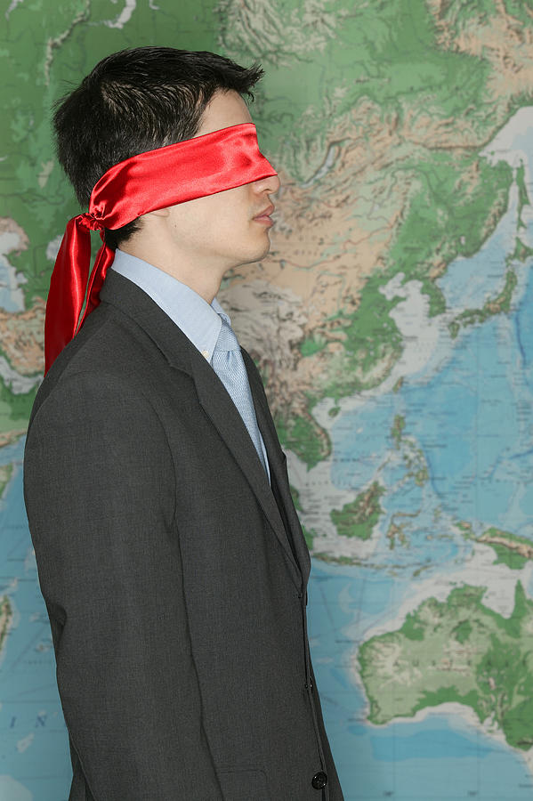 Blindfolded businessman in front of world map Photograph by Comstock Images