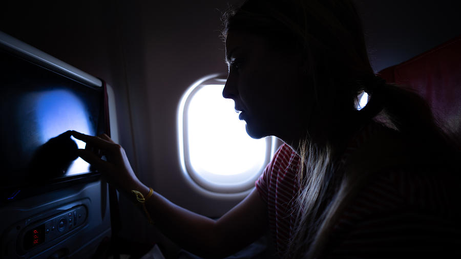 Blonde woman watching television on the airplane Photograph by Byakkaya