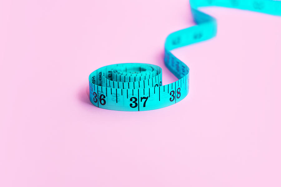Blue measuring tape on pink background. Photograph by Iryna Veklich