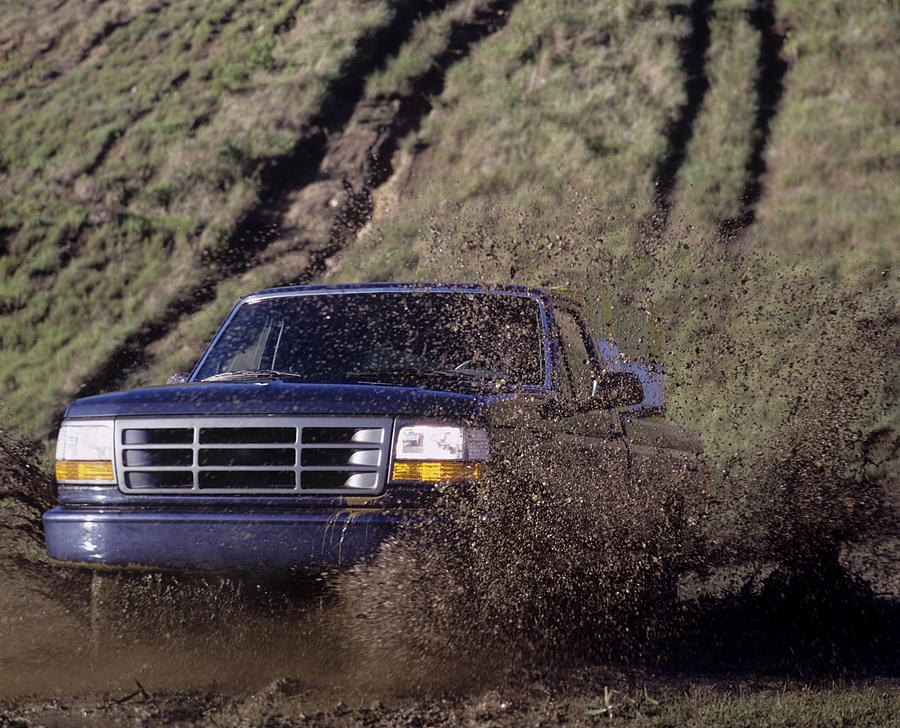 Blue pick up truck driving through a mud puddle Photograph by FabioFilzi