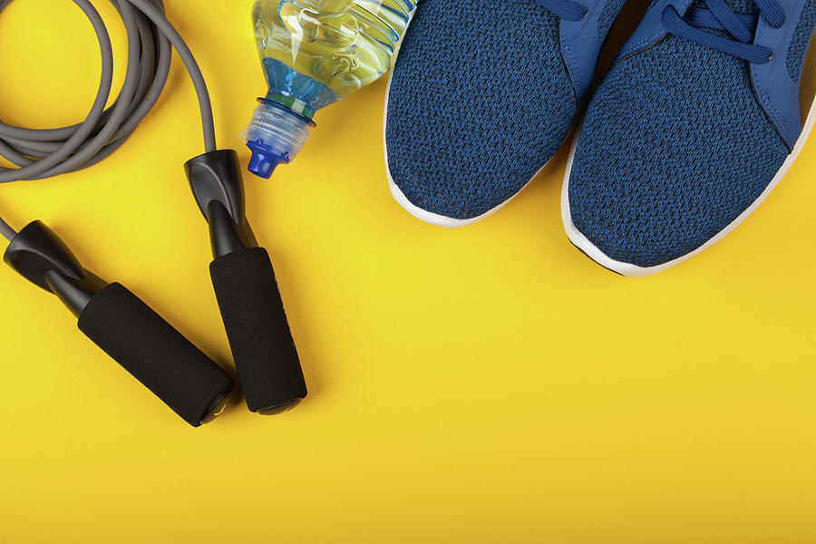Top Photograph - Blue sneakers, skipping rope and bottle of water on yellow background. Concept of healthy lifestile, everyday training and force of will by Michael Dechev