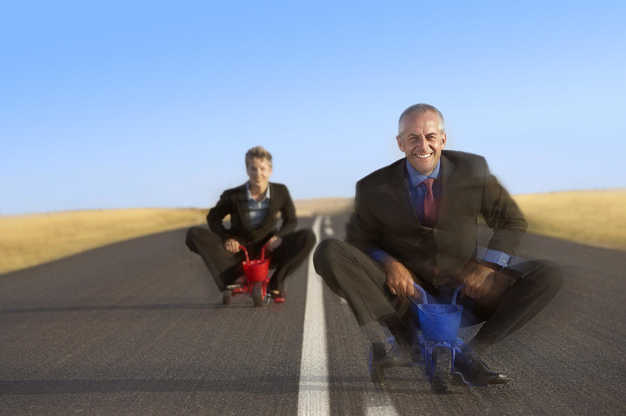 Blurred Motion Shot of Two Business Executives Riding Small Tricycles Photograph by John Cumming