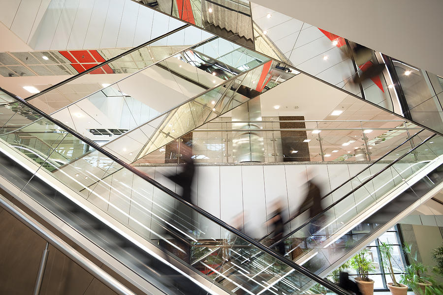 Blurred People on Escalator in Modern Glass Interior Photograph by Bim
