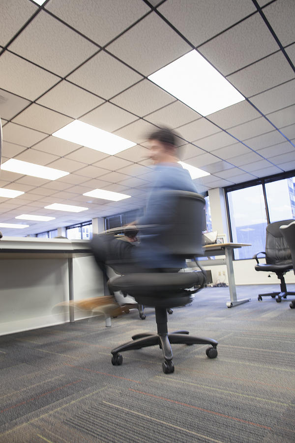 Blurred view of Caucasian businessman spinning in office chair Photograph by Jetta Productions Inc