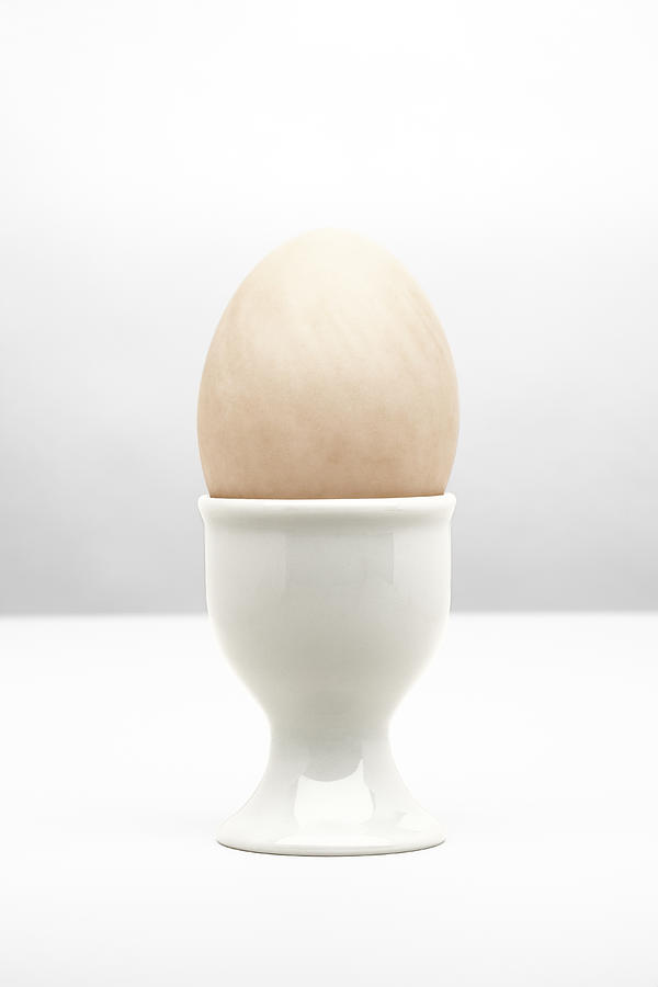 Boiled egg in white egg cup, close-up Photograph by Microzoa