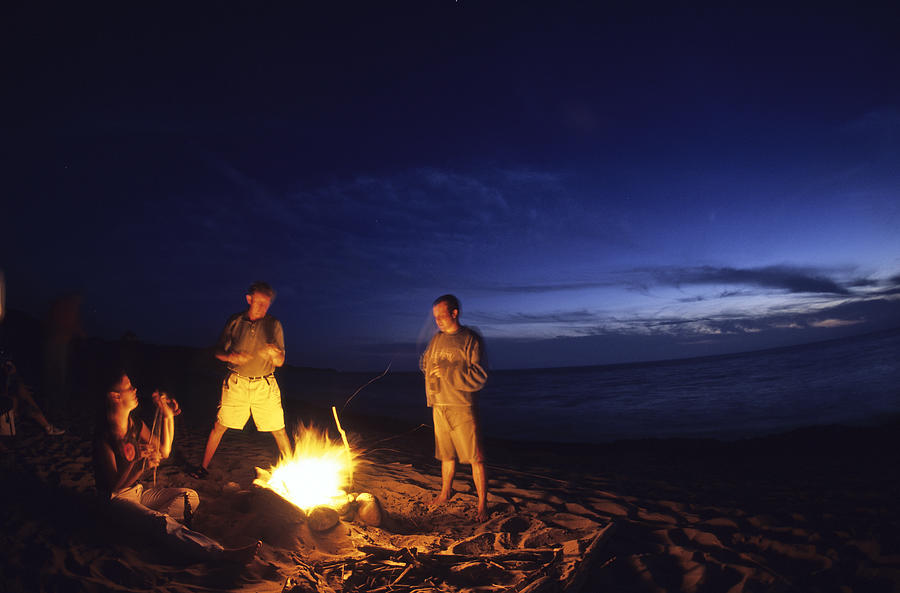 Bonfire on beach with ocean in background. Photograph by Heath Korvola