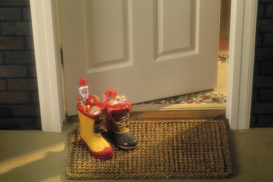 Boots filled with candy on door mat Photograph by Comstock