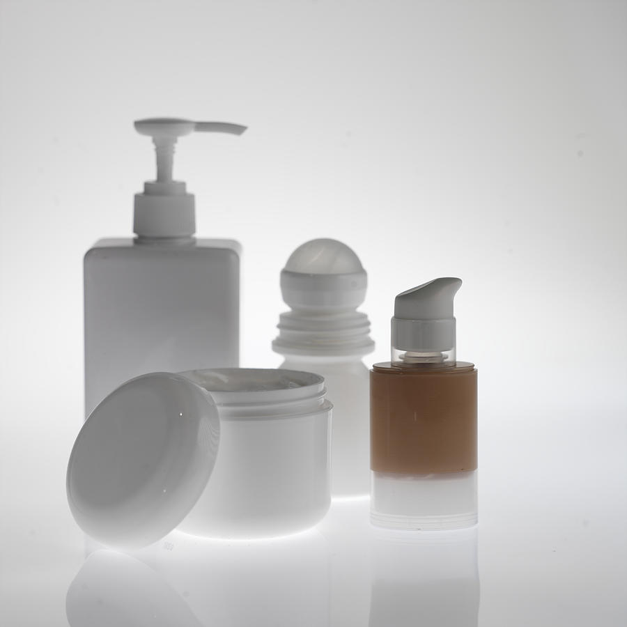 Bottle of make-up, deodorant, soap dispenser, moisturiser tub close up Photograph by Paul Tearle