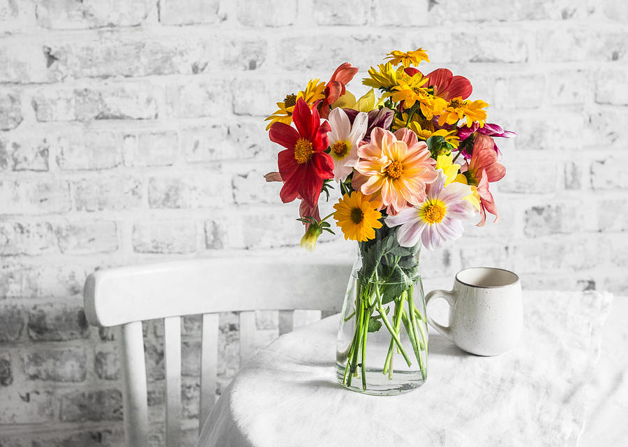 Bouquet of bright colorful autumn flowers on a bright table in a cozy light kitchen. Copy space, flat lay Photograph by OksanaKiian